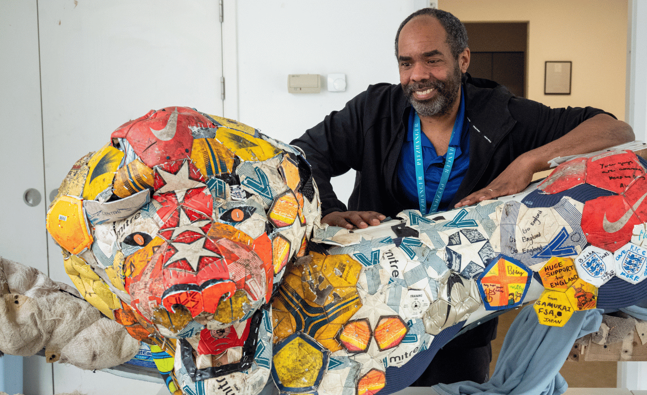 Artist Matt Small smiles beside a completed colorful lion sculpture made collaboratively with local children at Pitzhanger Manor.